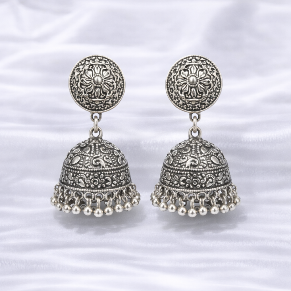 Intricate silver jhumka earrings on fabric