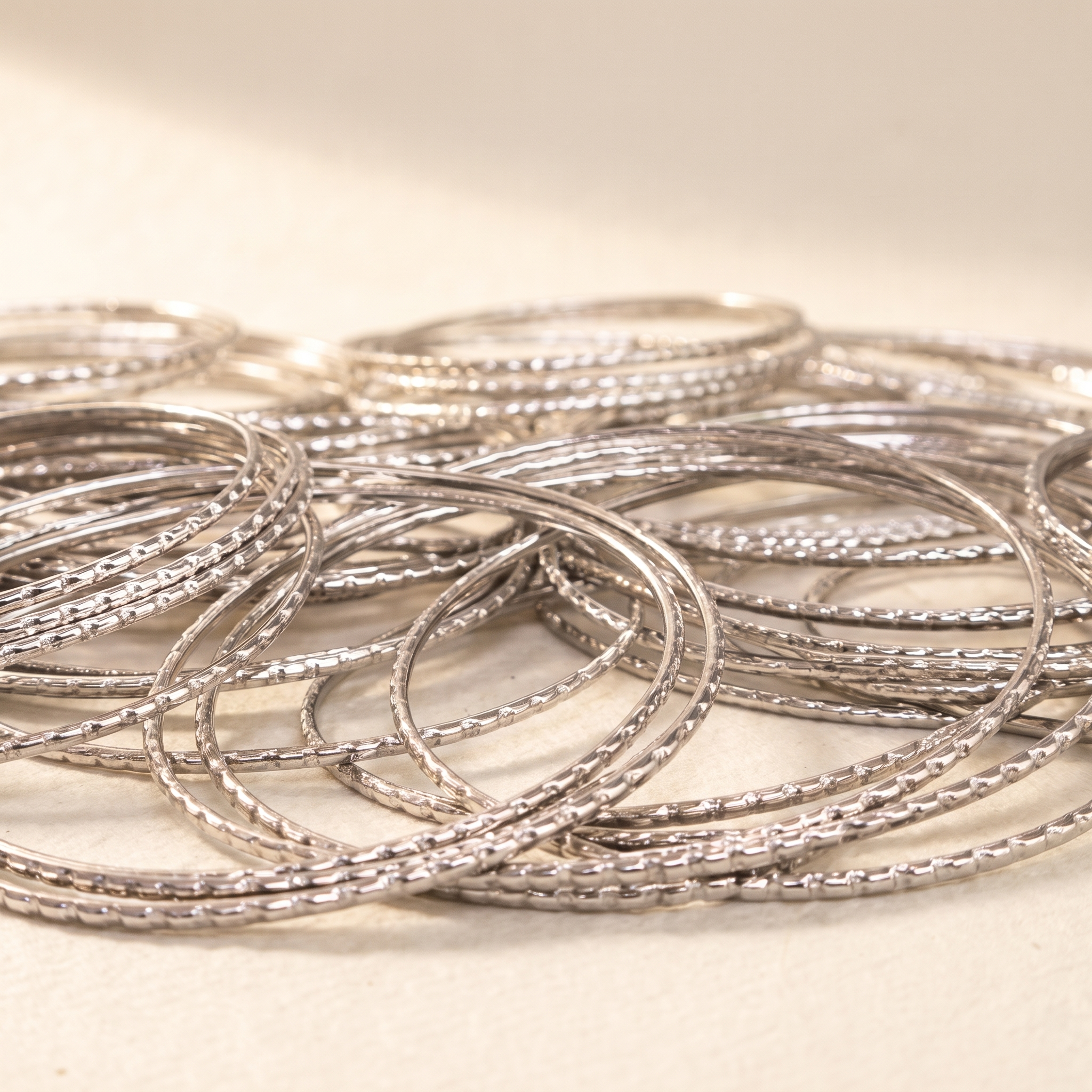 Classic stainless steel bangles set on warm ivory paper